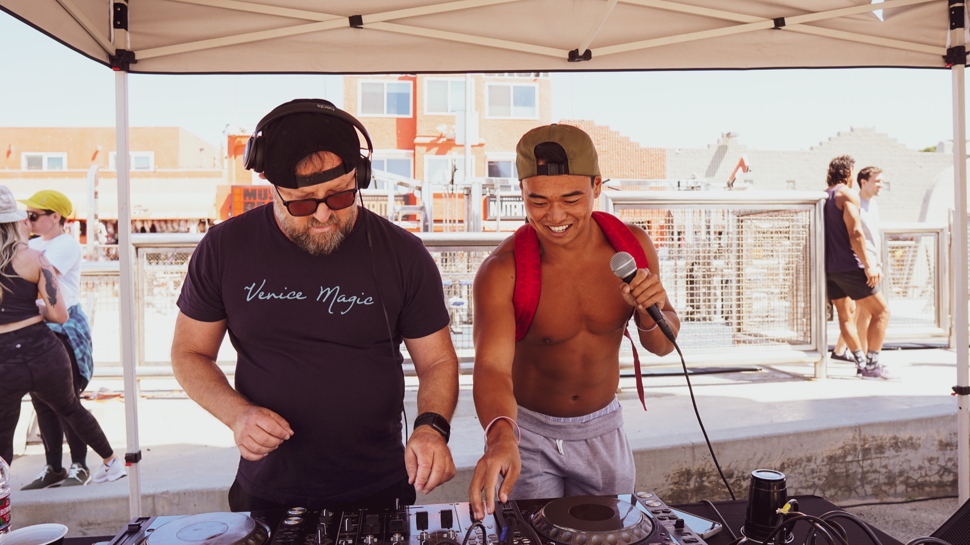 A DJ and emcee hyping up the crowd under a tent.