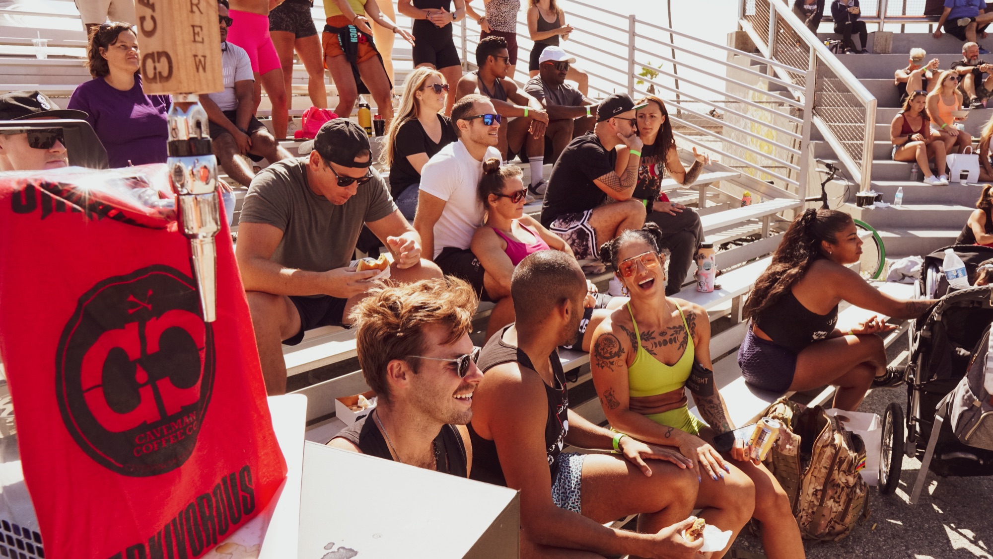 Spectators packed into the bleachers laughing in the sun.