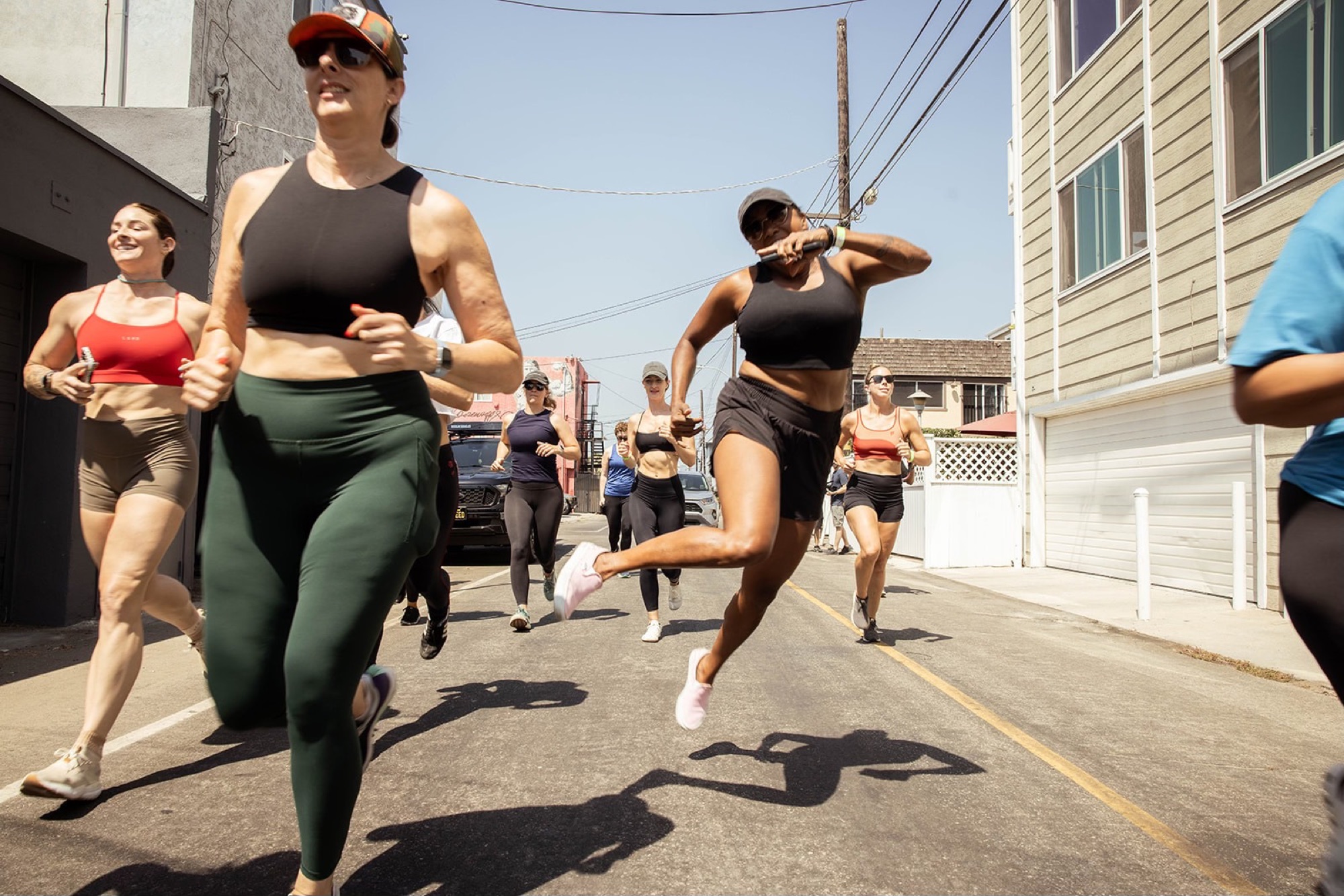 A pack of runners mid-stride on a sun-bleached Venice street, smiling and unbothered.